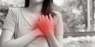 Woman holding her chest in pain outdoors