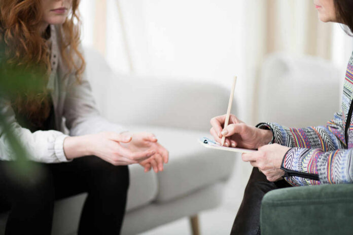 Two individuals engaged in a counseling session, one taking notes