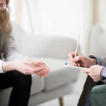 Two individuals engaged in a counseling session, one taking notes
