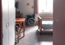 View of a hospital room featuring a patient bed and a wheelchair