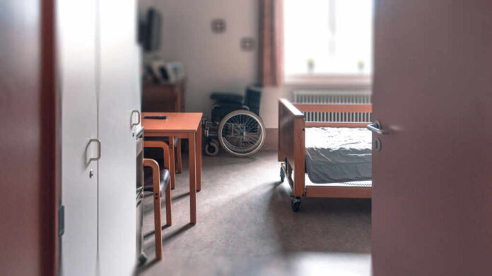 View of a hospital room featuring a patient bed and a wheelchair