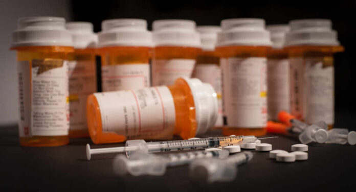 Various prescription medication bottles and syringes on a table