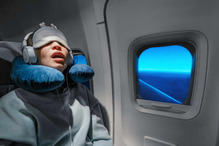 shutterstock_1417184849.jpg A passenger sleeping on an airplane with headphones and an eye mask