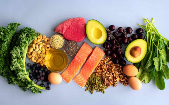 shutterstock_2131483793.jpg An assortment of healthy foods including fish, nuts, fruits, and vegetables arranged on a light background