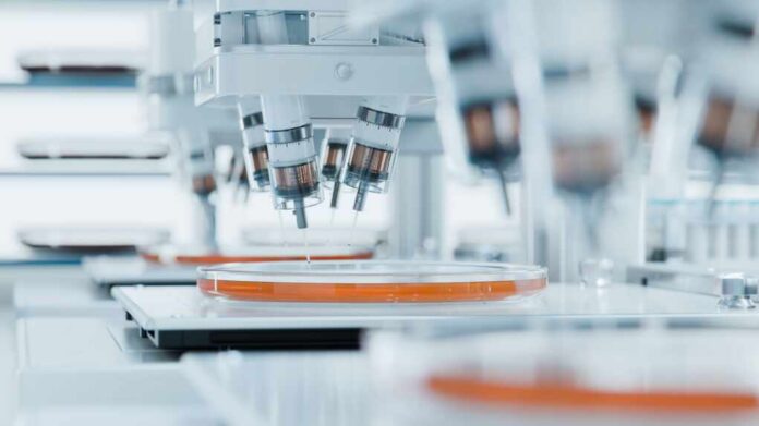 shutterstock_2422913707.jpg Automated laboratory equipment with robotic arms dispensing liquids into petri dishes