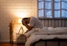 Paternal Depression: The Unseen Family Threat A person sitting on a bed with their head in their hands, expressing distress