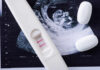 Pregnancy test next to an ultrasound image and two white tablets