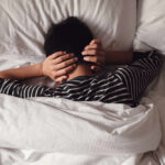 Child lying in bed with hands over ears