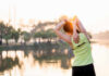 Banish Back Pain with This Simple Core Exercise A woman stretching her arms by a lake during sunrise