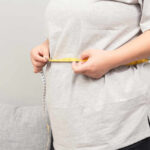 Person measuring their waist with a tape measure