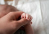 A close-up of a babys hand being held by an adult hand