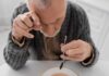 The Silent Killer Among Seniors Elderly man focusing intently on a spoon while preparing to eat
