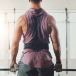 A muscular person preparing to lift a barbell in a gym setting