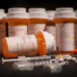 Various prescription medication bottles and syringes on a table