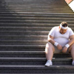 Avoid Cramping! The Pre-Workout Drink You Need An exhausted man in sportswear sitting on outdoor stairs, looking down.
