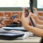 Students in a classroom using smartphones for a group activity
