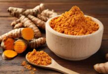 Turmeric’s True Benefits: What Science Says Turmeric powder in a wooden bowl with fresh turmeric roots