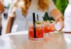 Close-up of cocktails on a table with a person reaching for one