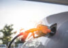 A fuel nozzle inserted into a cars gas tank during sunset