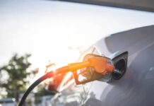A fuel nozzle inserted into a cars gas tank during sunset