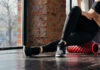 Yoga’s Role In Brain Healing And Inflammation Person using a foam roller for stretching in a fitness studio