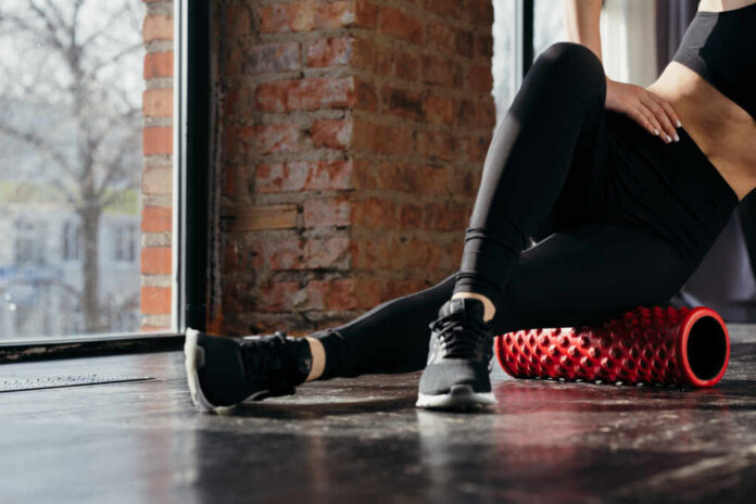 The,Exercises,At,The,Hip.,The,Girl,Crossed,Her,Legs Person using a foam roller for stretching in a fitness studio