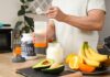 Removing the “Chalky” Taste from your Protein Shake Person preparing a protein shake with fruits and whey protein powder in a kitchen