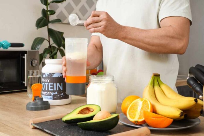Sporty,Muscular,Man,Pouring,Protein,Powder,Into,Bottle,For,Shake Person preparing a protein shake with fruits and whey protein powder in a kitchen