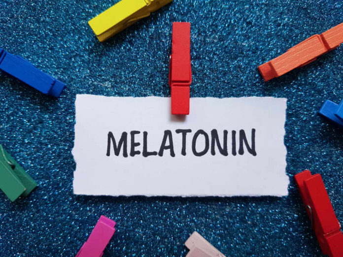 shutterstock_2482912627 A piece of paper with the word MELATONIN clipped by a red clothespin, surrounded by colorful clothespins on a blue glitter background