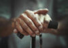 Two-Stage Aging Discovery Stuns Scientists Close-up of elderly hands resting on a walking cane