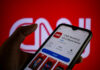 How Morning Scroll Affects Your Brain A hand holding a smartphone displaying the CNN news app against a red background