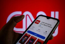 How Morning Scroll Affects Your Brain A hand holding a smartphone displaying the CNN news app against a red background