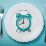 Alarm clock on a white plate with fork and knife