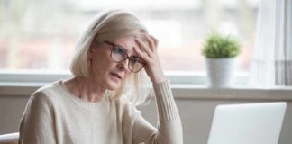 Older woman with glasses looking concerned at laptop