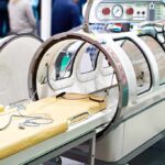 Hyperbaric oxygen chamber with open hatch and patient bed