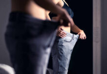 Algorithm Machine Fuels Deadly ‘Thin’ Trend Person trying on oversized pants in front of a mirror