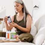 Woman reading a supplement bottle on a couch