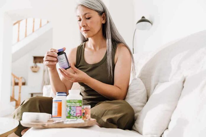 shutterstock_2061961277 Woman reading a supplement bottle on a couch