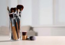 Clinic-Level Bacteria On Skincare Tools A collection of makeup brushes in a glass container on a table