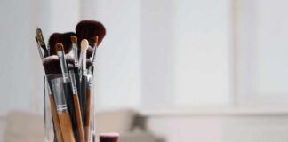 A collection of makeup brushes in a glass container on a table
