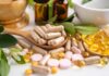 Beta-carotene: Sun Shield Or Cancer Trap? Various herbal supplements and vitamins arranged with leaves and a mortar