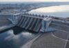 Aerial view of a large dam with water flowing through its gates