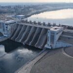 Aerial view of a large dam with water flowing through its gates