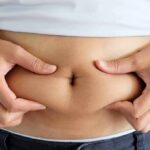 person pinching belly fat at the waist