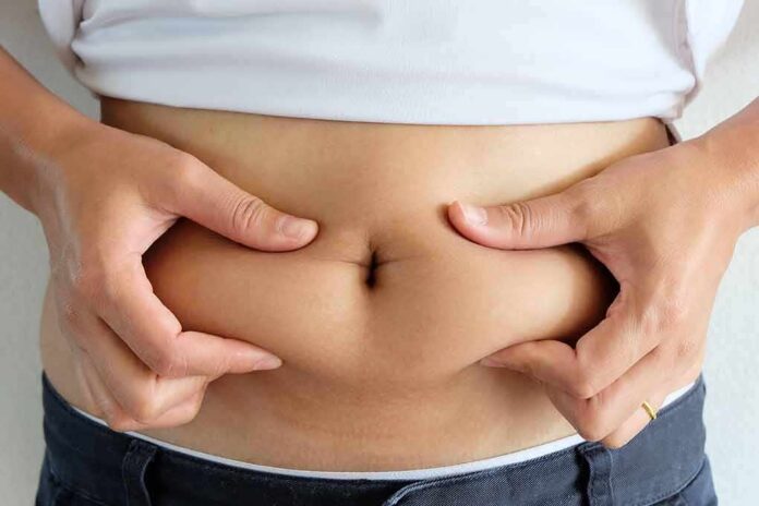 person pinching belly fat at the waist