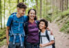The multifaceted benefits of walking for longevity A mother and her two children smiling while hiking on a forest trail