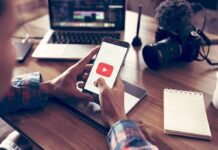 Attention Residue Is Taxing Brainpower Hands holding smartphone with video app icon at a workspace