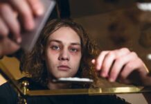 How The Wrong Zip Code Derails Addiction Recovery young person leaning over a table with hands arranging items