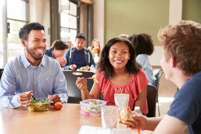 shutterstock_1131658817 Students eating lunch together at a cafeteria table