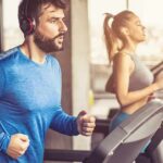 Man in blue long-sleeve running on a treadmill with headphones